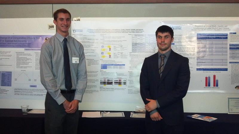 Two students stand on either side of a poster. 